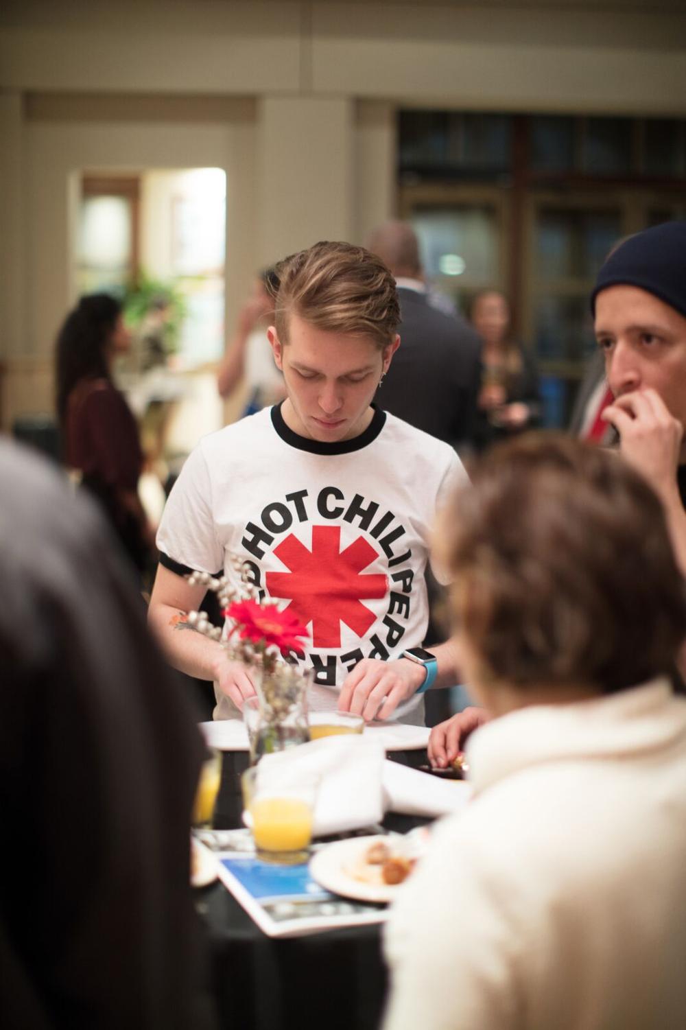 A person in a Red Hot Chili Peppers shirt looking at something on a small table